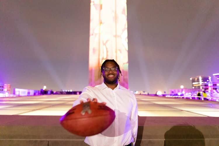 Paris Johnson Jr. holding a duke football in front of the WWI memorial