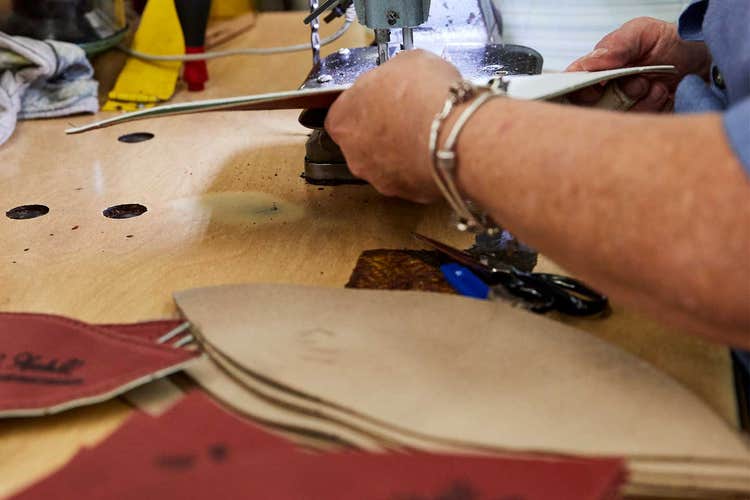 Two hands sewing panels of a duke football