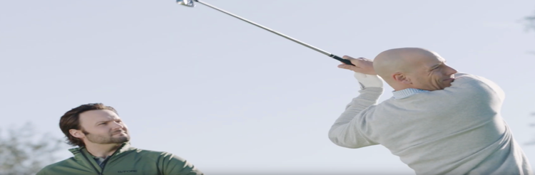 Jake Thurm watching over a man finishing his golf swing