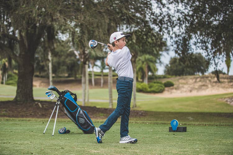 a young boy swinging a profile set driver