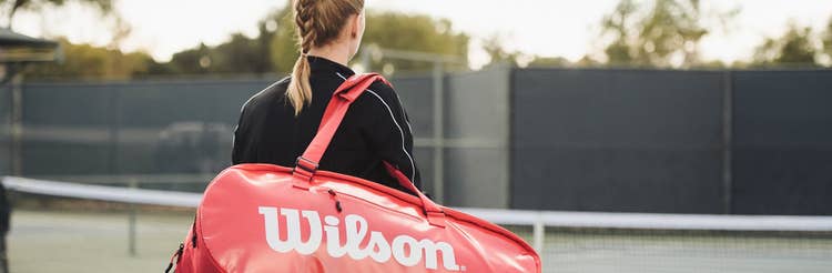 Player carrying tennis bag on court