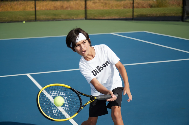 Young boy hitting a tennis ball on the court