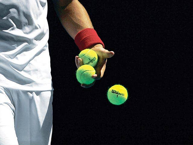 close up of player's hand holding tennis balls