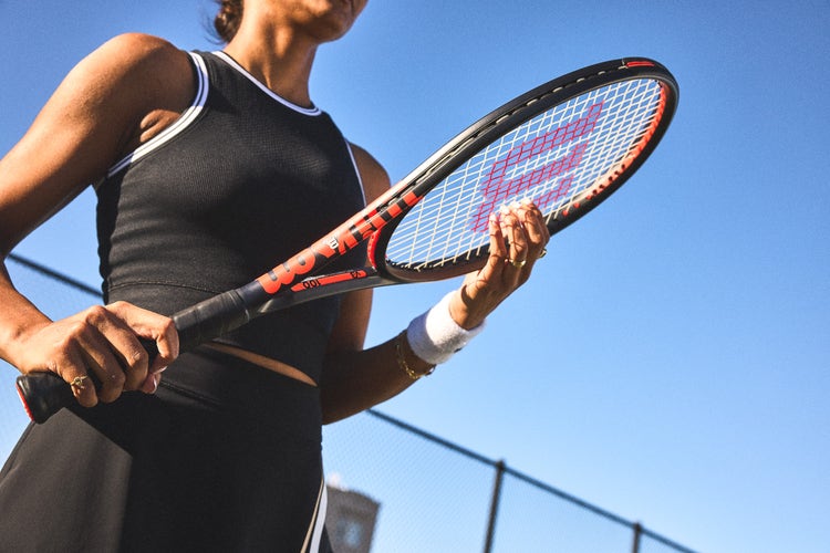 tennis player adjusting strings on racquet