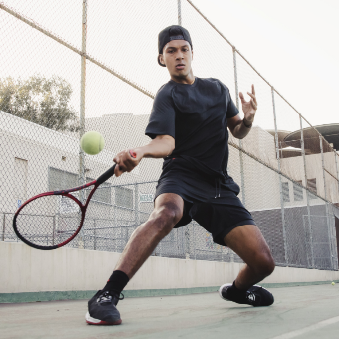 Man hitting a Wilson tennis ball on court