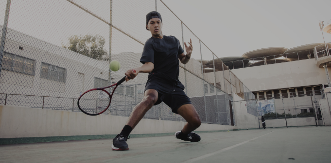 Man hitting a Wilson tennis ball on court