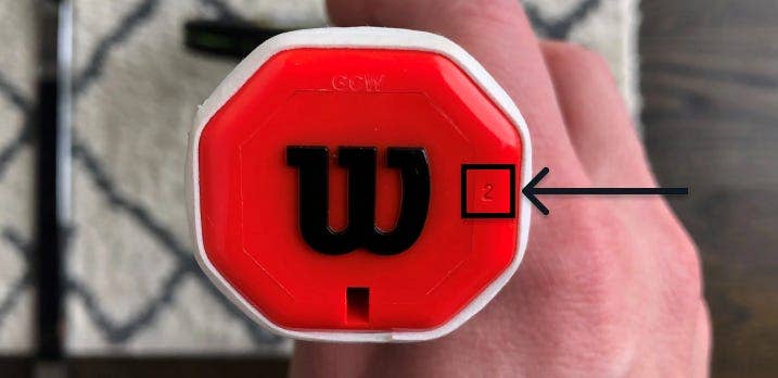 The bottom of a racket handle with the Wilson W on it
