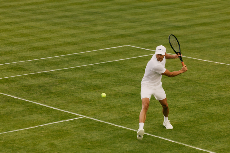 man dressed in Wilson tennis whites on a grass court