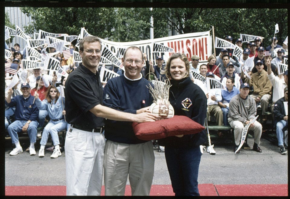 Considine, Wallace, and Davenport holding Wilson in front of crowded bleachers